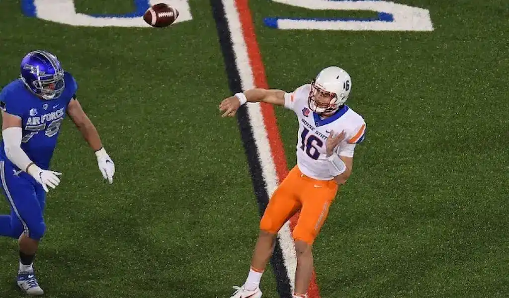 Boise State quarterback throws a pass while under pressure from an Air Force defender during a College Football game.