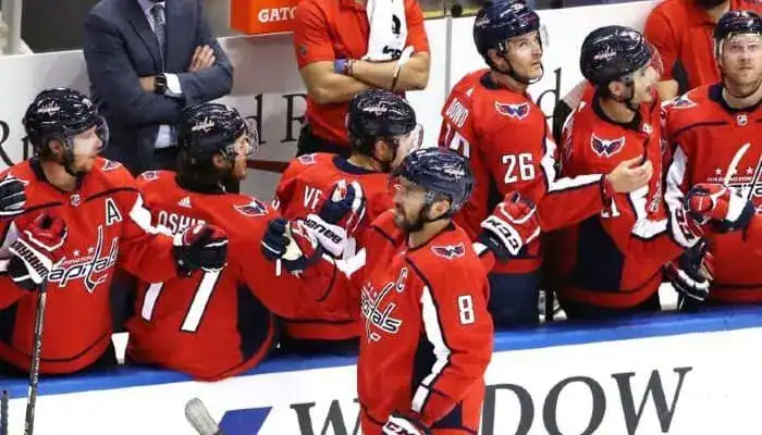 Washington Capitals players on the bench celebrating a goal, with Alex Ovechkin leading the excitement.