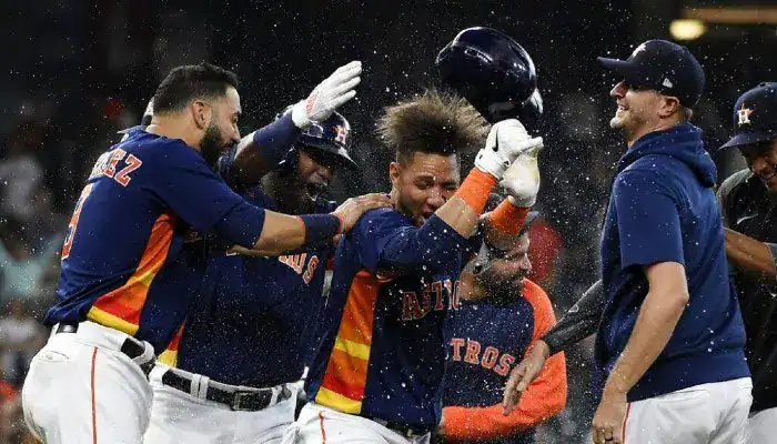 Houston Astros players celebrate a walk-off victory, pouring water on a teammate at home plate.