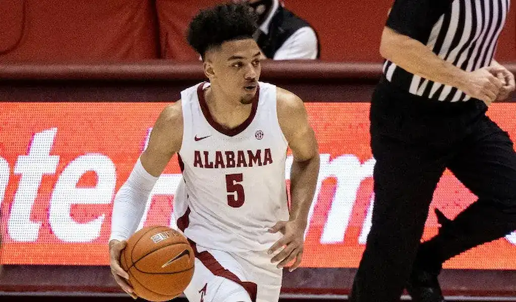 Alabama Crimson Tide basketball player dribbles the ball up the court during a college basketball game.