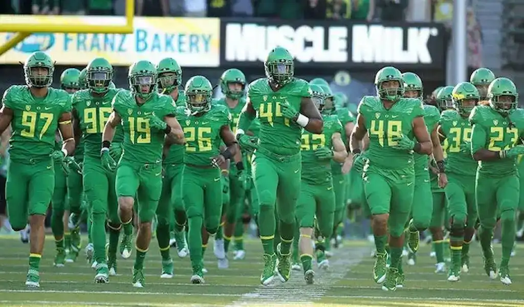 Oregon Ducks football team runs onto the field in green uniforms before a college football game.