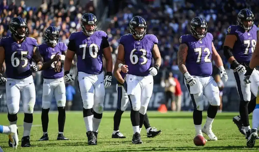 Baltimore Ravens offensive line walking onto the field during an NFL game.