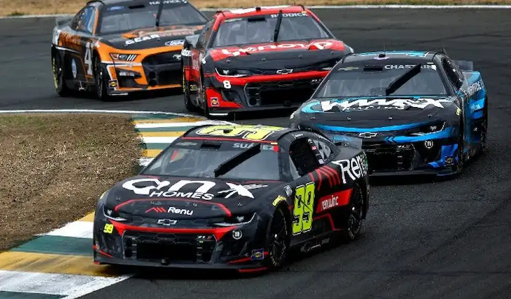 Gambling News 11 NASCAR cars racing at the Bank of America Roval 400, with the No. 39 car leading through a corner.