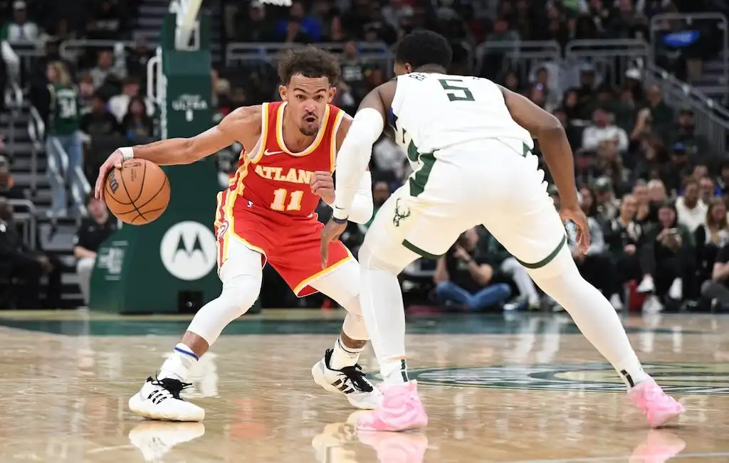 An Atlanta basketball player dribbles at the top of the key while being closely guarded by a defender.