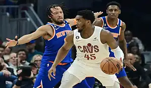 Cleveland Cavaliers player driving with the ball while being defended by New York Knicks players during an NBA game.