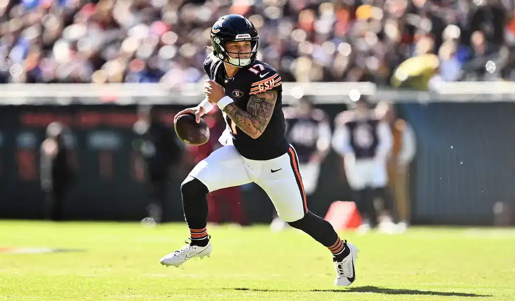 Chicago Bears quarterback rolling out of the pocket while looking to pass during an NFL game.