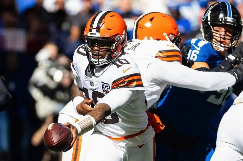 A Cleveland Browns quarterback extends the ball to hand it off during a play.