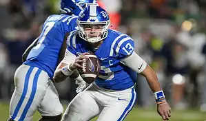 Duke Blue Devils quarterback runs with the football against NC State Wolfpack defense during NCAA game on October 10, 2023.