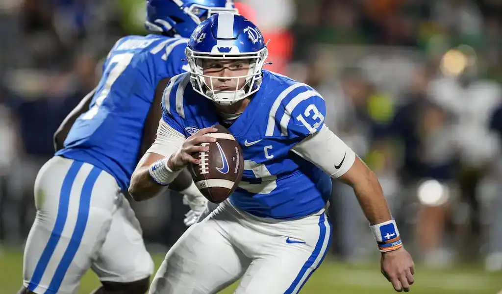 Duke Blue Devils quarterback runs with the football against NC State Wolfpack defense during NCAA game on October 10, 2023.