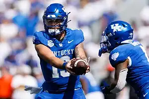 Kentucky Wildcats quarterback hands off the football to a teammate.