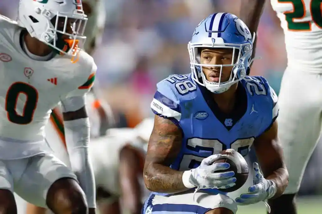 North Carolina Tar Heels player runs the ball against Miami Hurricanes defense.