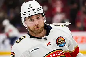 Florida Panthers hockey player in a white jersey and helmet skates during a game with a focused expression.