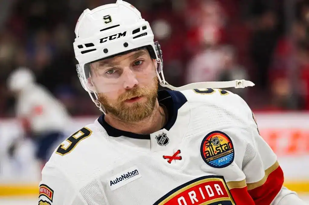 Florida Panthers hockey player in a white jersey and helmet skates during a game with a focused expression.
