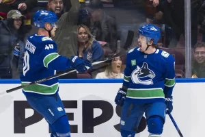 Two Vancouver Canucks players celebrate on the ice in front of excited fans during a game.