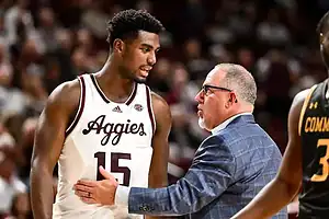 Texas A&M Aggies player talks with coach on the sideline during a timeout.