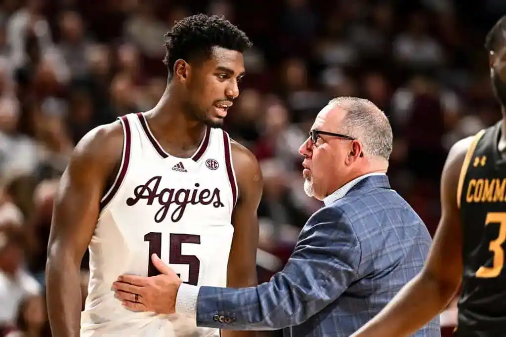 Texas A&M Aggies player talks with coach on the sideline during a timeout.