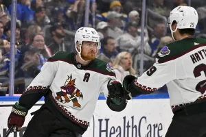 An Arizona Coyotes player bumps a teammate during an NHL game.