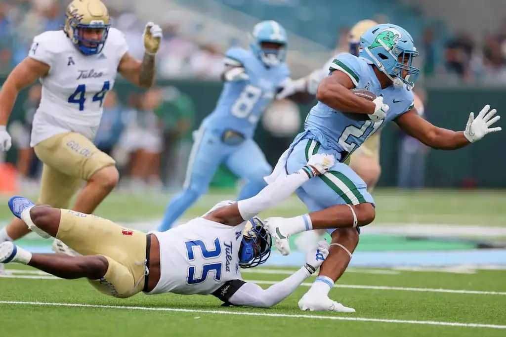 College football player #21 makes a run, tackled by #25.