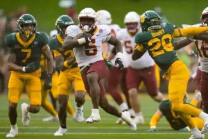 College football game, featuring a player from Iowa State running with the ball while being pursued by Baylor University players.