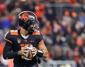 Oregon State quarterback scans the field while holding the football in a game.