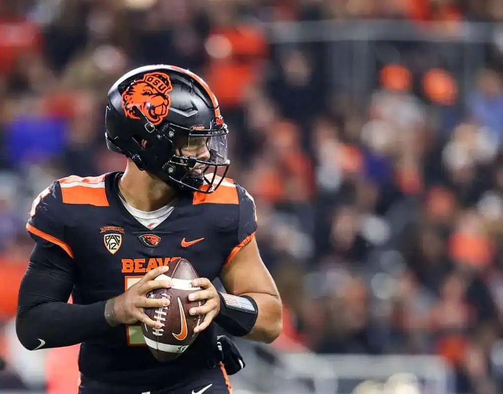 Oregon State quarterback scans the field while holding the football in a game.