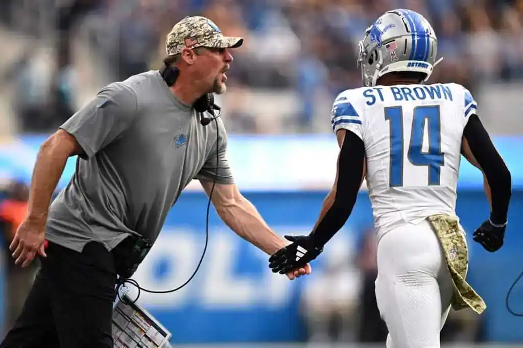 7 Detroit Lions coach and wide receiver Amon-Ra St. Brown exchange an intense handshake on the sideline.