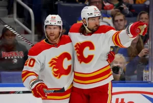 Two Calgary Flames players celebrate on the ice during a game.