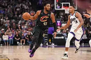 Cleveland Cavaliers player dribbling the ball while being defended by a Sacramento Kings player during an NBA game.
