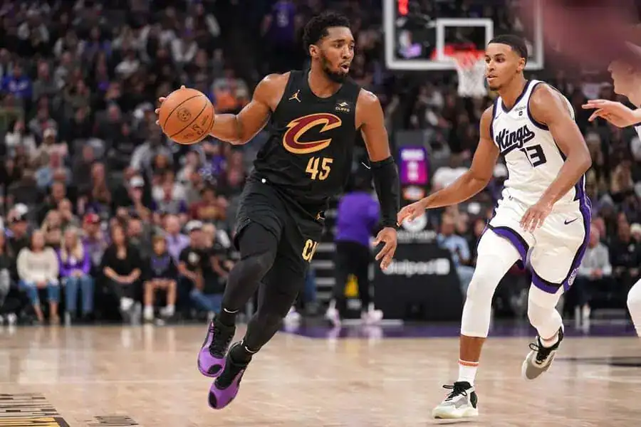 Cleveland Cavaliers player dribbling the ball while being defended by a Sacramento Kings player during an NBA game.