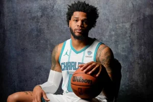 A Charlotte basketball player poses for a portrait while holding a basketball.