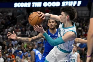 Charlotte Hornets player drives to the basket with the ball extended in one hand.