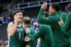 Colorado State player celebrates with teammates and coaches on the sideline.