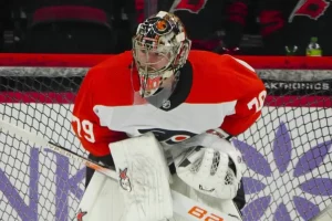 Philadelphia Flyers goalie stands in front of the net, focused and ready during an NHL game.