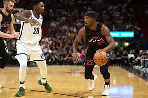 Miami Heat’s number 22 dribbles the ball while being guarded by a Brooklyn Nets player during an NBA game.
