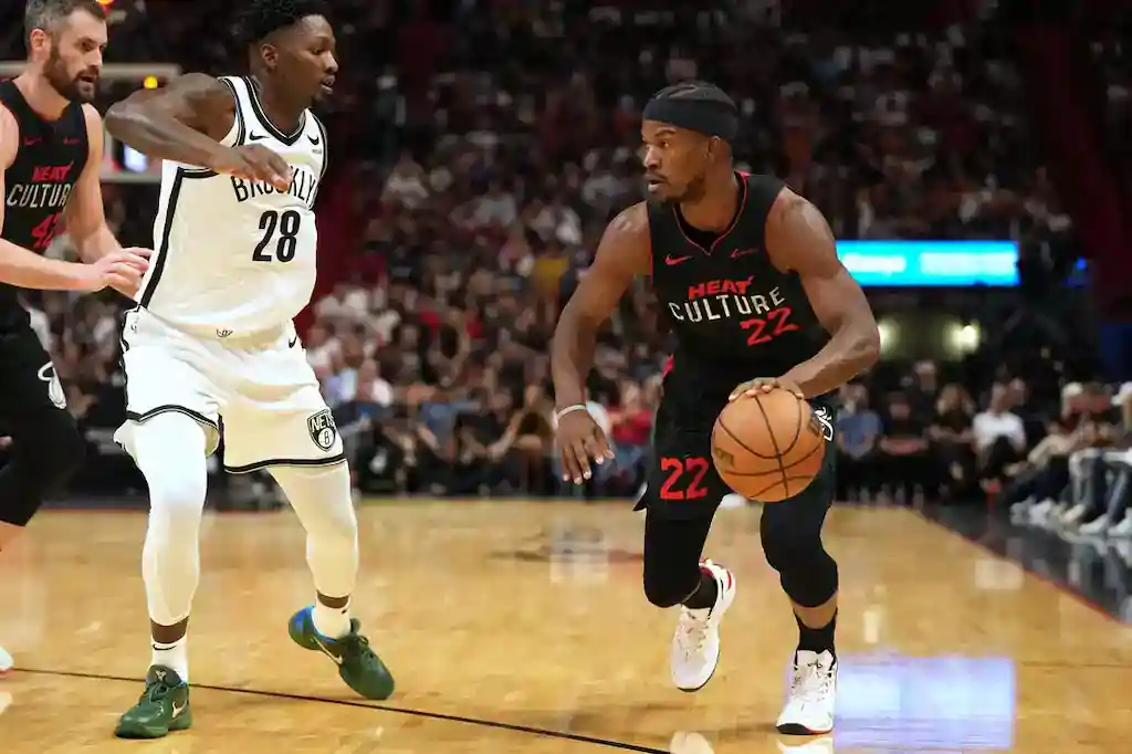 5 Miami Heat’s number 22 dribbles the ball while being guarded by a Brooklyn Nets player during an NBA game.