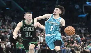 Charlotte Hornets player drives to the basket while defended by Boston Celtics player during NBA action.