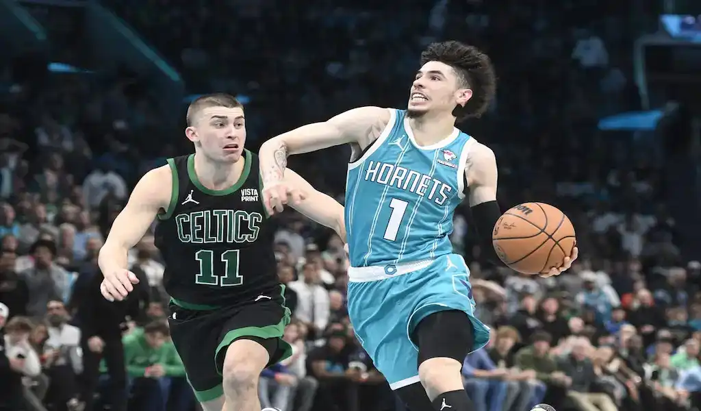 Charlotte Hornets player drives to the basket while defended by Boston Celtics player during NBA action.