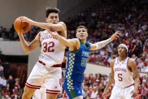 An Indiana basketball player secures the ball while being closely defended by an opposing player.