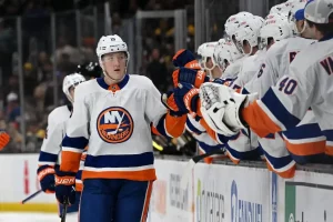 New York Islanders player skates past the bench and fist bumps teammates after a play.