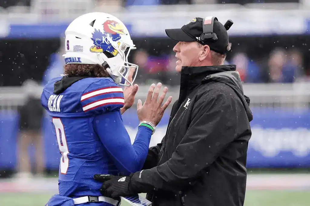 Kansas coach talks to quarterback on field.