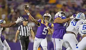 LSU Tigers quarterback throws a pass under pressure against Texas A&M Aggies during college football action.