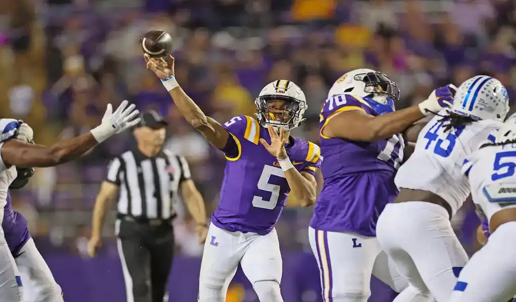 LSU Tigers quarterback throws a pass under pressure against Texas A&M Aggies during college football action.