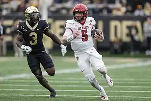 NC state player carrying the ball and opponent chasing