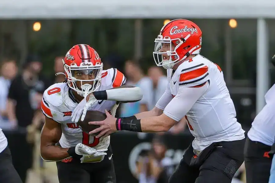 Oklahoma State Cowboys quarterback hands the football to a running back during a play.