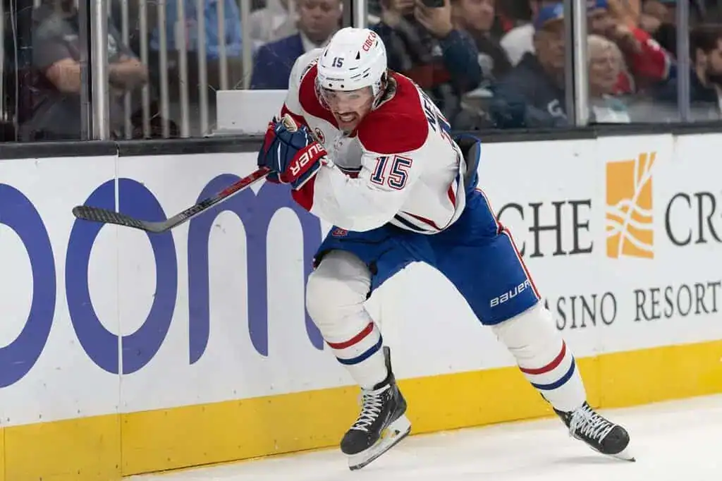 Montreal Canadiens player skating aggressively along the boards, holding his stick while wearing a white jersey with red and blue accents.
