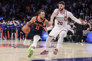New York Knicks guard Jalen Brunson drives to the basket while being closely guarded by Phoenix Suns center.