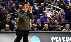 Pittsburgh Panthers coach shouts instructions from the sideline during NCAA basketball game against Jacksonville Dolphins.