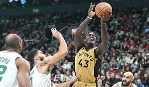 Toronto Raptors player driving to the basket against Boston Celtics defenders during an NBA game.