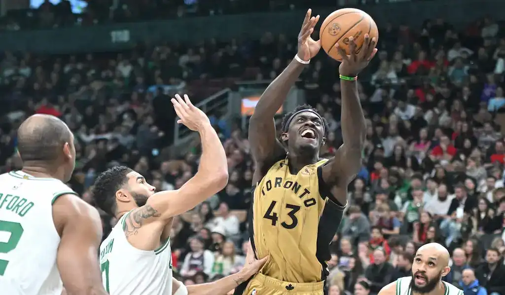 Toronto Raptors player driving to the basket against Boston Celtics defenders during an NBA game.