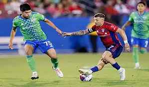 FC Dallas player controls the ball while pressured by a Seattle Sounders FC defender during an MLS match.